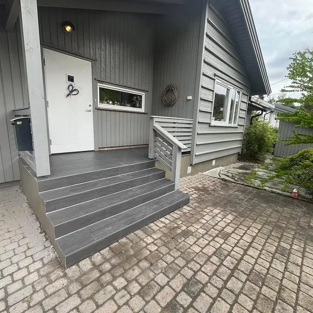 Inngangsparti med grå flislagt trapp foran hus
